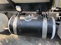 Close-up of a black fuel tank with silver bands on a Peterbilt 340 truck with various fittings and a gauge attached