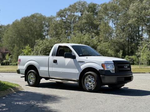 A white 2014 Ford F-150 pickup truck with a single cab and a short bed parked in a clear area