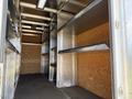 A 2016 Ford Transit with a spacious cargo area featuring metal shelving along the sides and a wooden back wall
