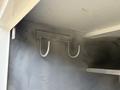 A metal hook mounted on a gray surface designed for hanging items