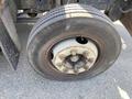 A close-up view of a worn tire mounted on a 1996 GMC Top Kick with visible rust on the wheel rim and five lug nuts securing it in place