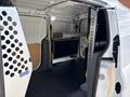 A 2021 Ford Transit Connect interior shows a cargo space with metal shelving and black flooring, designed for utility and storage needs
