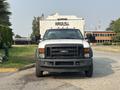 A white 2009 Ford F-550 truck with a black grille parked on a pathway facing forward