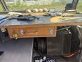 A wooden dashboard with a small drawer featuring stickers and various tools and items scattered on its surface inside a 2009 Workhorse W62 vehicle