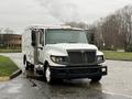 A white 2014 International TerraStar truck with a black grille has an enclosed cargo area and is parked on a wet surface