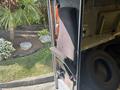 A 2012 Ford E-450 driver's seat is positioned in an open door with visible upholstery and seatbelt mechanism