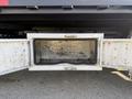 A diamond plate storage compartment is open underneath a truck revealing an empty metal interior