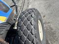 A close-up of a large textured tire of a 2010 New Holland T4050 tractor showcasing its rugged tread pattern