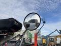 A side mirror of a 2013 Freightliner 114SD reflecting the truck itself and showing a clear sky with scattered clouds