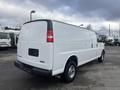 A 2022 GMC Savana white cargo van parked with its rear side visible showing chrome wheels and no visible windows