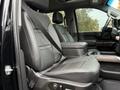 Interior of a 2022 GMC Sierra 3500HD featuring leather seats with seat belts and a center console between the front seats