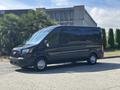 A black 2025 Ford Transit T-350 van is parked, featuring a spacious design and rear cargo doors, showcasing its utility and modern style