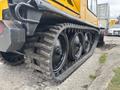 A close-up view of a yellow 2004 Bombardier SW48 with large black rubber tracks showcasing the tread design and wheels