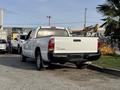 A white 2013 Toyota Tacoma is parked in a lot with its tailgate open and a visible hitch at the rear