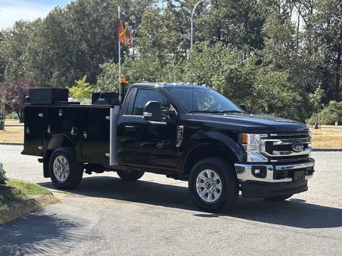 A black 2022 Ford F-350 SD truck with a utility bed featuring toolboxes and an orange warning light on the cab