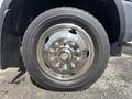 Close-up of a shiny metal wheel with a circular design and multiple bolts mounted on a black tire of a 2016 RAM 5500