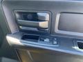Close-up of the door handle and window control panel of a 2015 RAM 1500 with a textured black interior finish