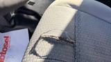 A close-up of a torn fabric seat in a 2016 Ford F-150 showing frayed edges and visible wear and tear