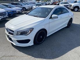 A 2014 Mercedes-Benz CLA-Class in white with black alloy wheels and a sporty design positioned at an angle