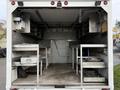 A 2007 Ford E-350 interior with a spacious cargo area featuring metal work tables and shelves for storage