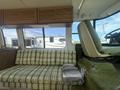 Interior of a 1976 GMC Motorhome featuring a green plaid sofa and a green upholstered driver's seat with various controls visible