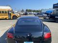 A black 2015 Bentley Continental GT viewed from the rear with distinctive tail lights and a sleek design