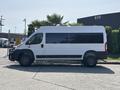 A side view of a white 2022 RAM Promaster 350 van with large windows and black accents on the lower body and wheels