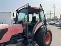 A red and black 2010 Kubota M6040 tractor with an open door revealing the driver's seat and control panel