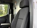 A black fabric driver's seat inside a 2023 Mercedes-Benz Sprinter with a headrest and armrest visible