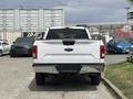 A rear view of a white 2017 Ford F-150 truck with chrome accents and clear taillights parked in a lot