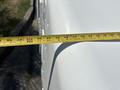 A white 2012 Ford Econoline van with a measuring tape placed across its side indicating dimensions