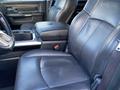 A black leather seat and console in the interior of a 2017 RAM 1500 with a textured pattern and a RAM logo on the headrest