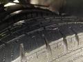 A close-up of three dark tires stacked with visible tread patterns and a slight sheen of moisture on their surfaces