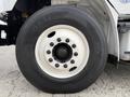 The image shows a close-up of the wheel and tire of a 2021 Freightliner M2 106 with a black tire and a white wheel rim featuring multiple lug nuts