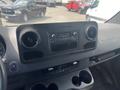 Interior dashboard of a 2024 Mercedes-Benz Sprinter featuring a central audio system and control buttons with cup holders below