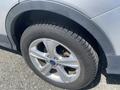 A close-up view of a wheel from a 2015 Ford Escape featuring silver alloy rims and a black tire with visible tread pattern