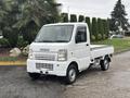 A white 2008 Suzuki Carry mini truck with a flatbed and a compact design is parked, featuring a simple front grille and headlights