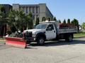 A 2008 Ford F-450 SD with a flatbed and a red snow plow attachment in front