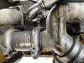 Close-up of the exhaust system featuring metallic pipes and a turbine on a 2018 John Deere 350 with visible wear and oil residue