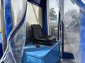 A black seat mounted on a blue platform inside a transparent enclosure representing a 2023 Bitimec SC415
