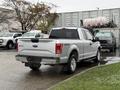 A silver 2015 Ford F-150 truck parked with a crew cab and 4x4 badge visible on the tailgate
