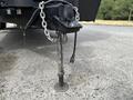 A metallic trailer hitch with a chain attached located on a flat surface