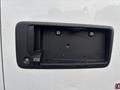 The rear door handle area of a 2022 GMC Savana with a camera and empty license plate mount showing visible water droplets