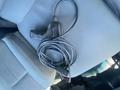 A handheld device with a cord lying on a vehicle seat
