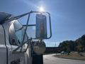 A 2004 Ford F-750 truck with a side mirror and reflective surface catching sunlight