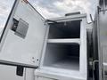 An open compartment of a 2014 Ford F-550 truck showing a spacious interior with shelves and a clean white surface