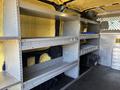 Interior of a 2016 Ford Transit 150 with metal shelving units installed along one side