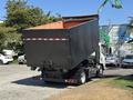 A 2016 Isuzu NPR-HD truck with a large tilted dump bed revealing an empty cargo area