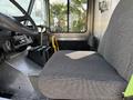 Interior view of a 2017 Freightliner MT45 showing the driver's seat with a gray fabric cover and a dashboard area with various controls and storage compartments