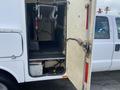 A 2015 Ford F-550 with an open side door revealing a spacious cargo area equipped with hooks and a metal grip handle